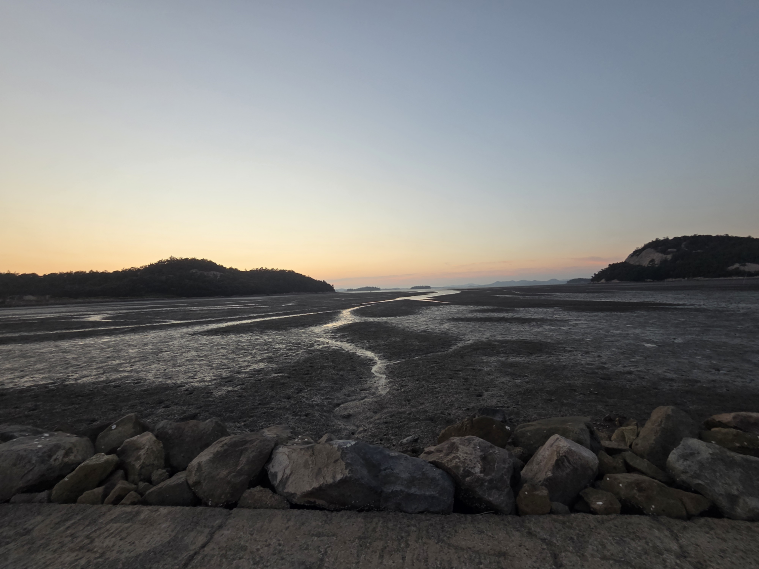 Sunset over Soakdo tidal flats with winding water channels across the mudflat